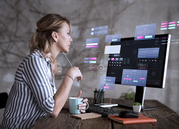 Stockfoto: Designerin arbeitet am Computer mit futurischer Benutzeroberfläche – UX-Design, UI-Entwicklung und kreative Digitalarbeit am modernen Arbeitsplatz.